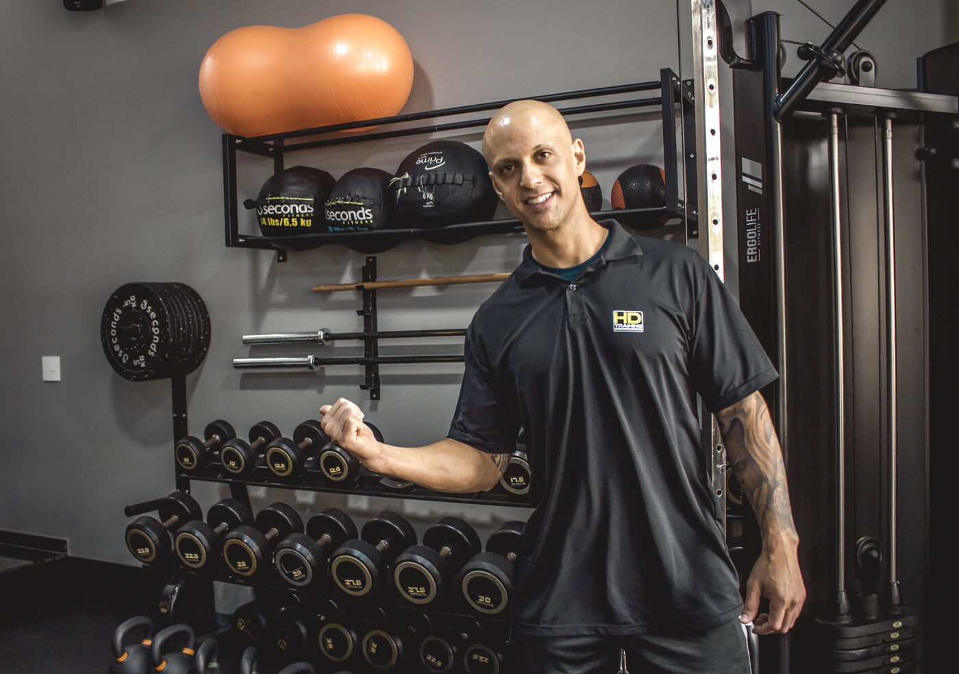 Professor da HD Training ao lado do rack de halteres